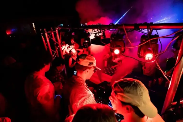 Crowd beneath red club lighting