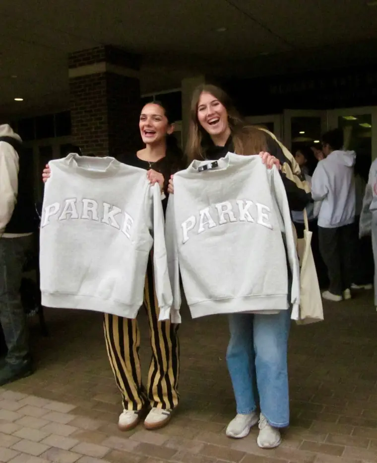 Two guests holding up sweatshirts