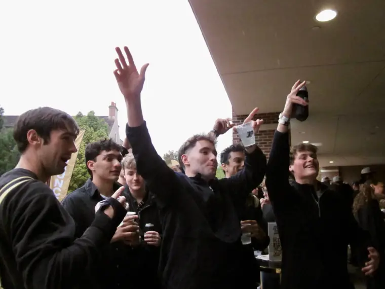 People raising their hands beside the DJ booth
